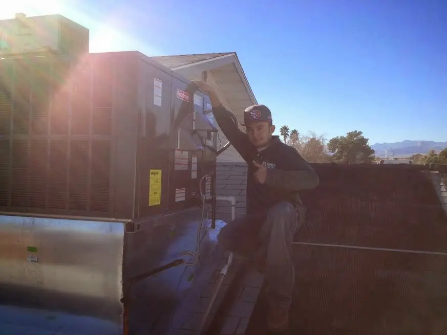HVAC technician performing Air Duct Cleaning on a rooftop unit in Ojus